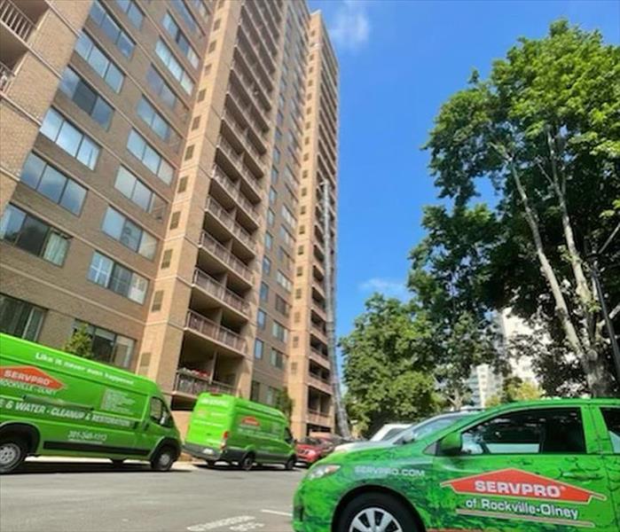 Tall condo building with green SERVPRO trucks
